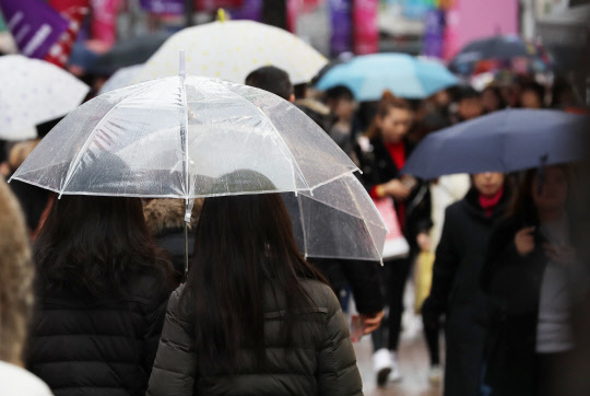 겨울비 내리는 26일 오후 서울 명동을 찾은 시민들이 우산을 쓰고 걷고 있다.